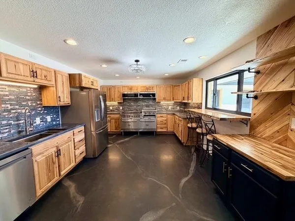 a living room with stainless steel appliances furniture a rug and a window