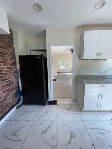 a view of a refrigerator in kitchen and an empty room