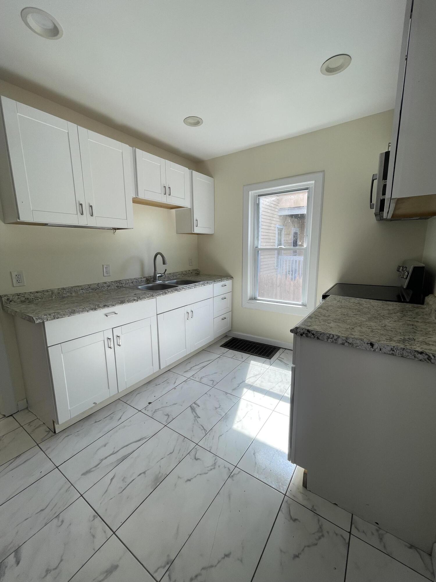 1664 West Main Street Stroudsburg, PA 18360 - Photo 9 of 29 a kitchen with granite countertop a sink a stove and white cabinets