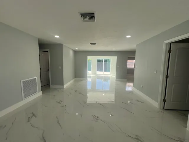 an empty room with windows and refrigerator