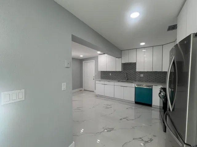 a kitchen with granite countertop a stove sink and refrigerator