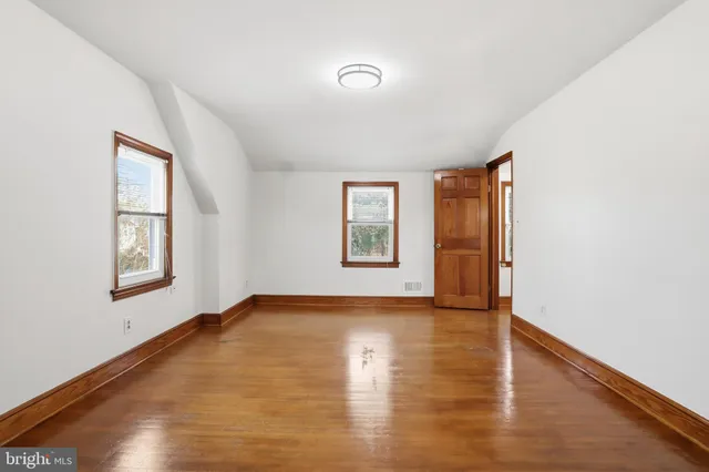 a view of an empty room with window and wooden floor
