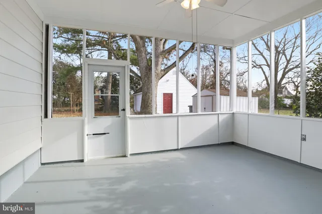 a view of an empty room with a window and chandelier fan