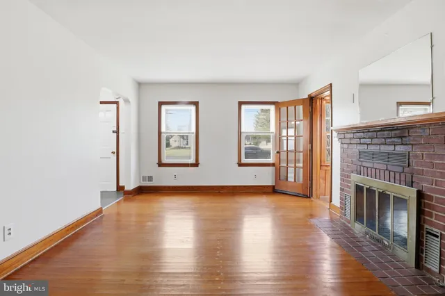 an empty room with wooden floor and fireplace