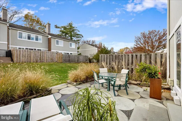 a view of a patio with table and chairs and potted plants with wooden floor and fence