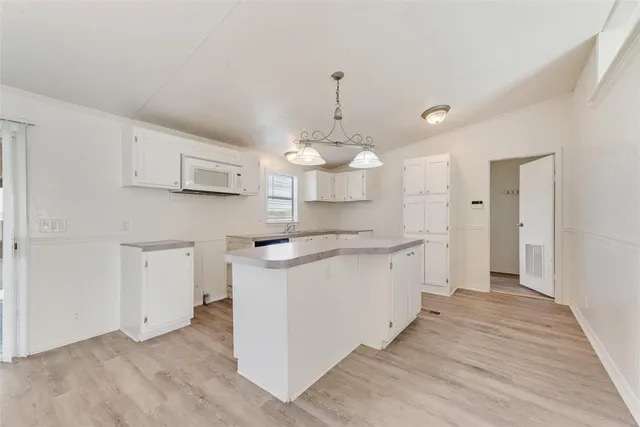 a kitchen with kitchen island white cabinets and white appliances