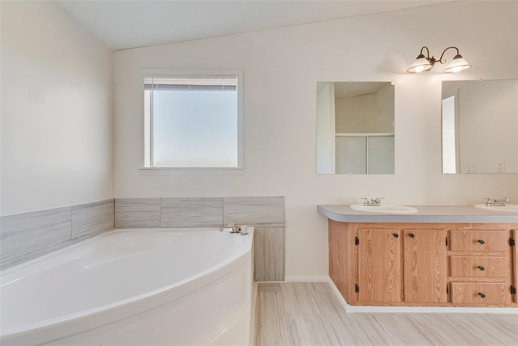 817 Kaufman Street Rosser, TX 75158 - Photo 22 of 29 a bathroom with a bathtub a mirror a sink and vanity