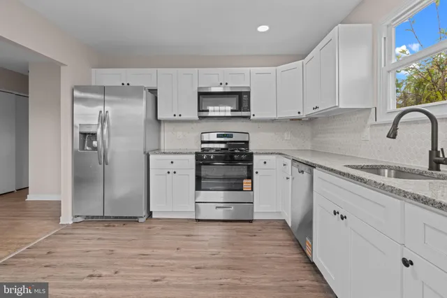 a kitchen with granite countertop white cabinets and stainless steel appliances