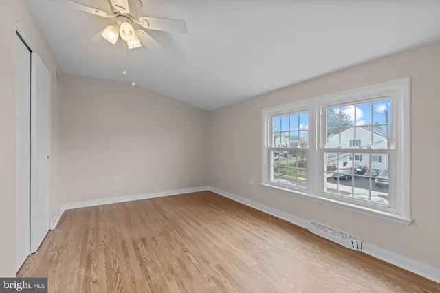 a view of an empty room with a window and wooden floor