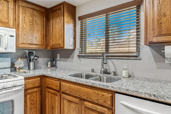a kitchen with granite countertop a sink a window and cabinets