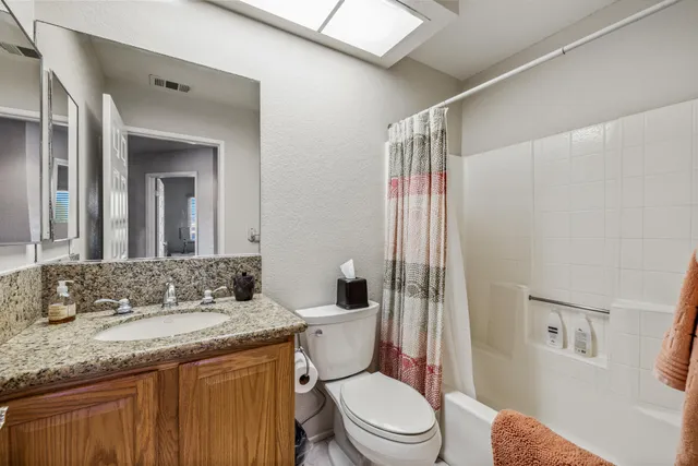 a bathroom with a granite countertop toilet a sink and a mirror
