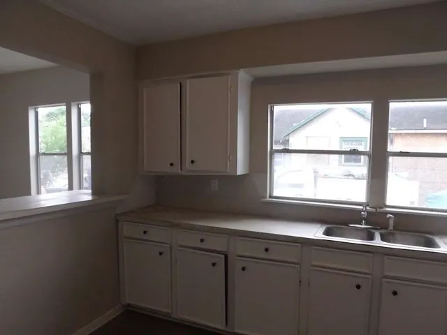a kitchen with a sink window and cabinets