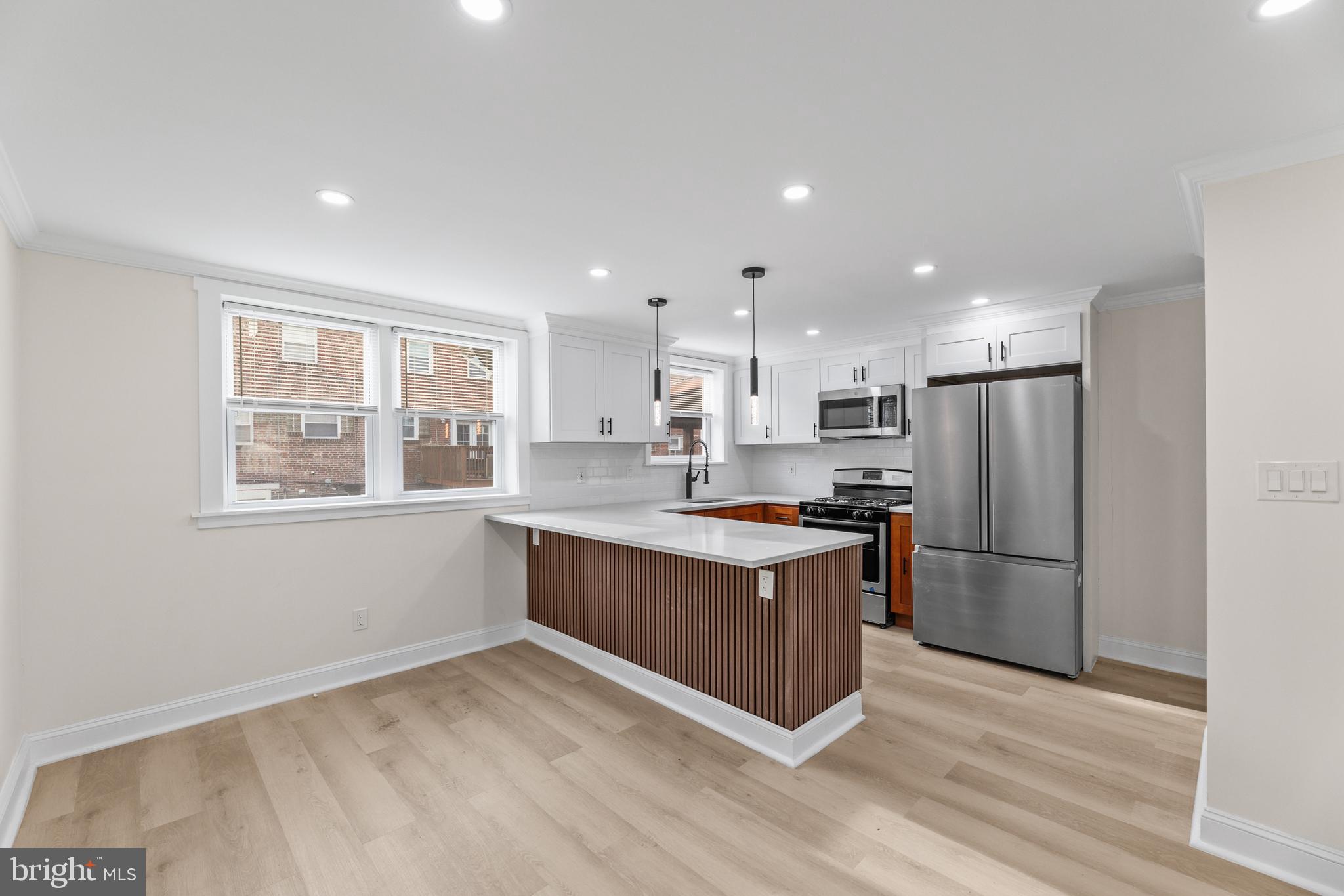 7920 Provident Street Philadelphia, PA 19150 - Photo 11 of 32 a large kitchen with stainless steel appliances granite countertop a stove a sink dishwasher a refrigerator and white cabinets with wooden floor