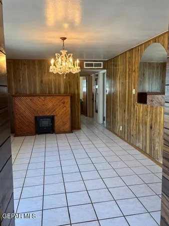 a room with a chandelier and kitchen view