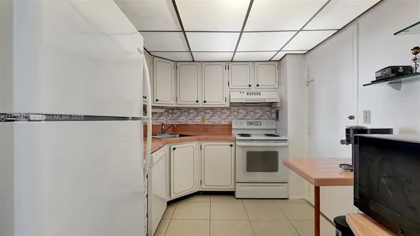 a kitchen with stainless steel appliances a stove a refrigerator and white cabinets