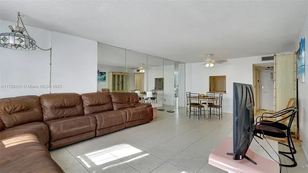 a living room with furniture a dining table and a refrigerator