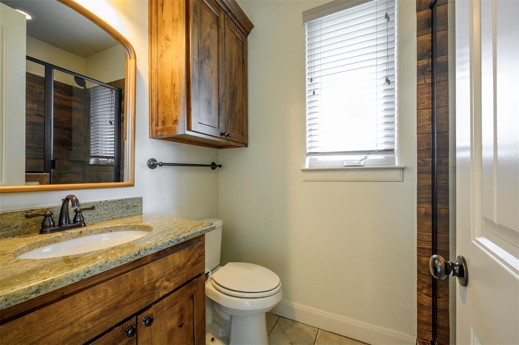 1003 Buckner Road Lipan, TX 76462 - Photo 23 of 31 a bathroom with a granite countertop toilet sink and mirror