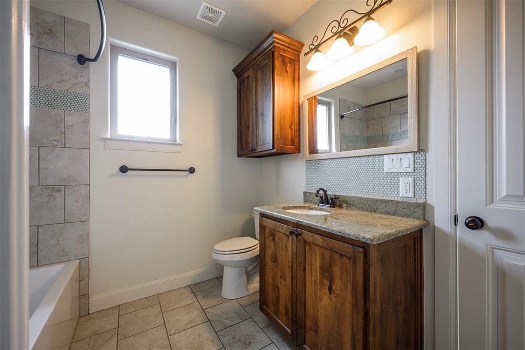 1003 Buckner Road Lipan, TX 76462 - Photo 25 of 31 a bathroom with a granite countertop sink toilet and mirror