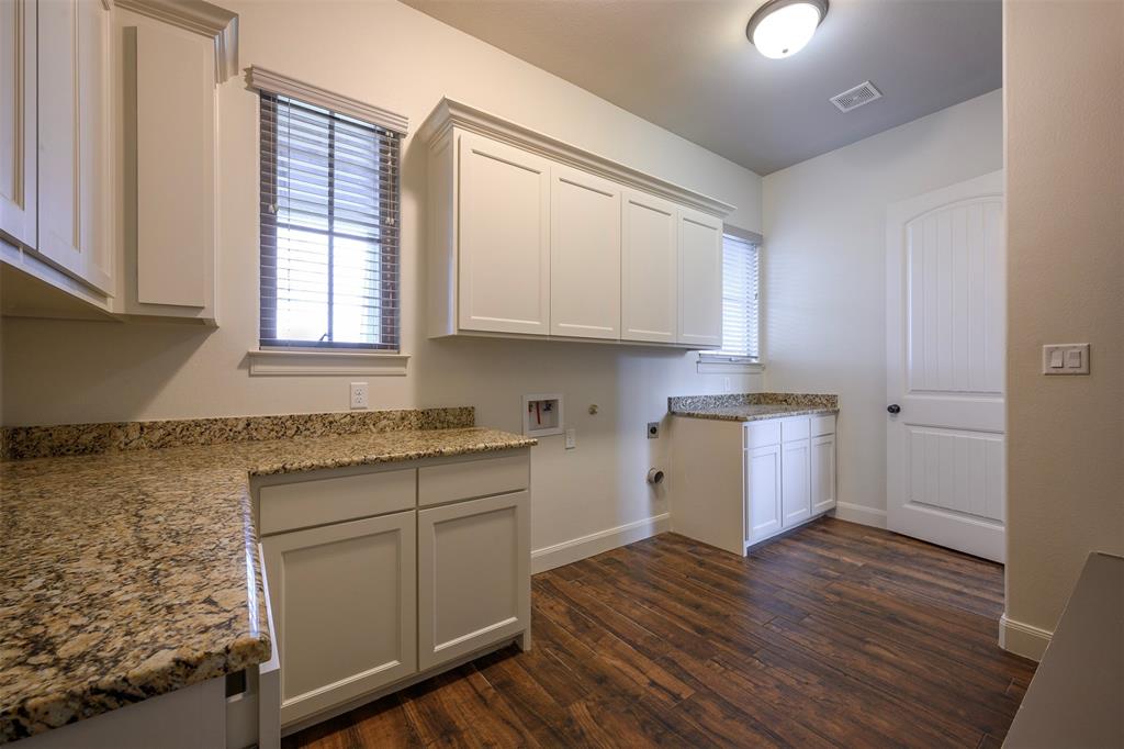 1003 Buckner Road Lipan, TX 76462 - Photo 30 of 31 a kitchen with granite countertop wooden cabinets a sink and dishwasher with wooden floor
