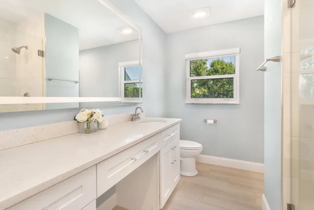 a bathroom with a granite countertop toilet sink and mirror