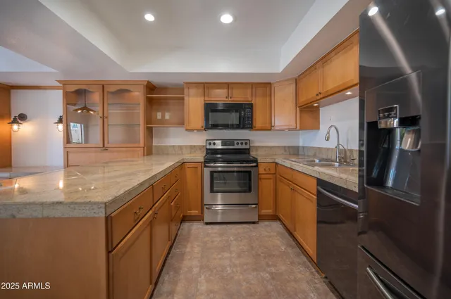 a large kitchen with stainless steel appliances granite countertop a stove top oven a sink and dishwasher
