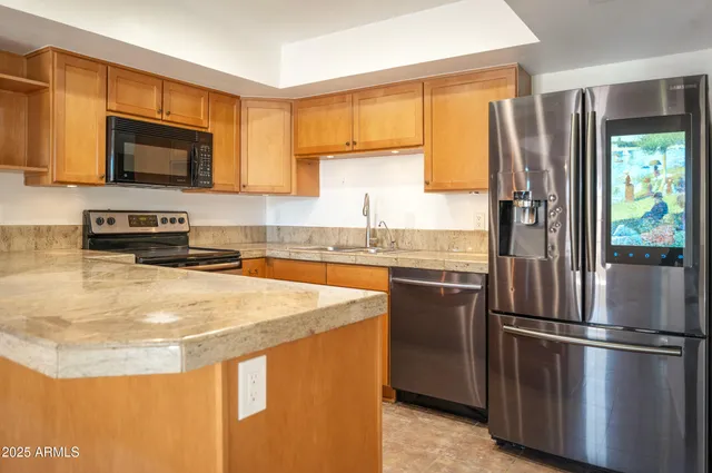 a kitchen with stainless steel appliances granite countertop a refrigerator a stove top oven a sink and dishwasher