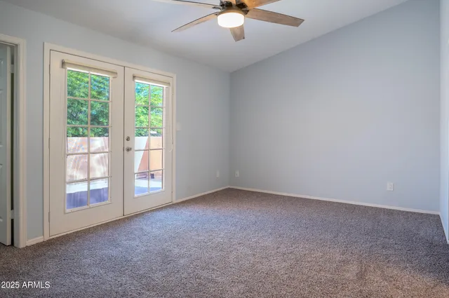 an empty room with windows and ceiling fan