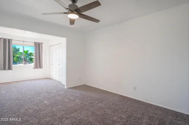 an empty room with windows and fan