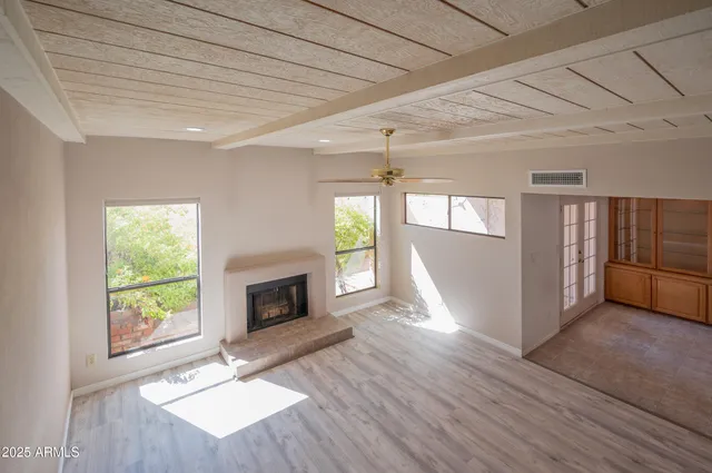 a view of an empty room with wooden floor fireplace and a window