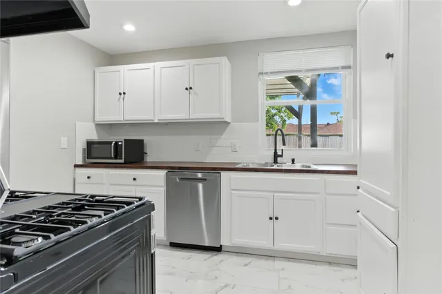 a kitchen with granite countertop white cabinets and stainless steel appliances