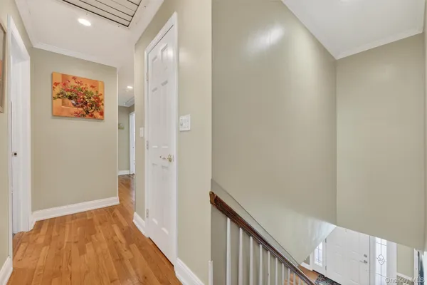 a view of a hallway with wooden floor and a bathroom
