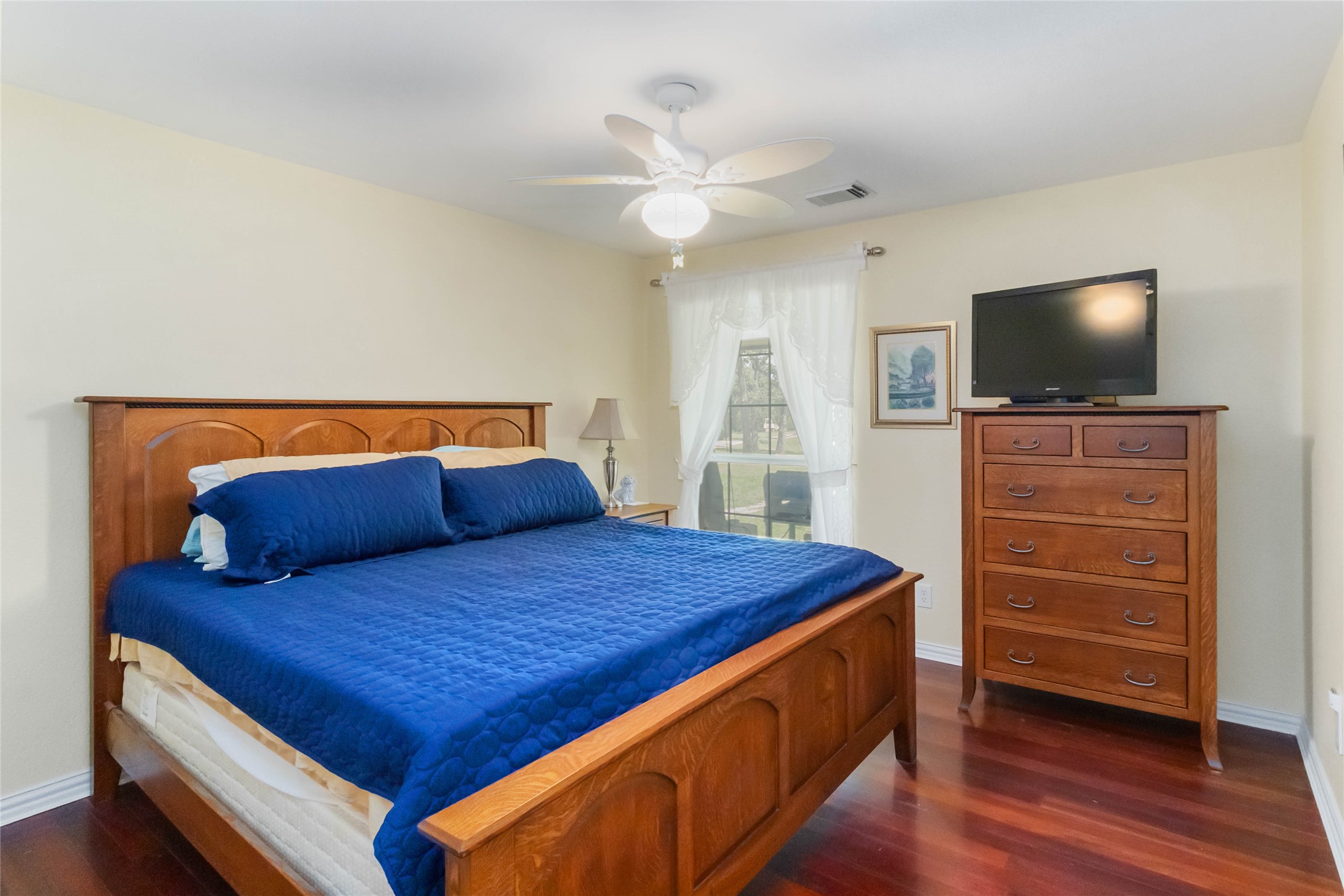 1208 Jeddo Road Rosanky, TX 78953 - Photo 17 of 40 Hardwood floors and a ceiling fan create a comfortable atmosphere in this well-appointed bedroom.
