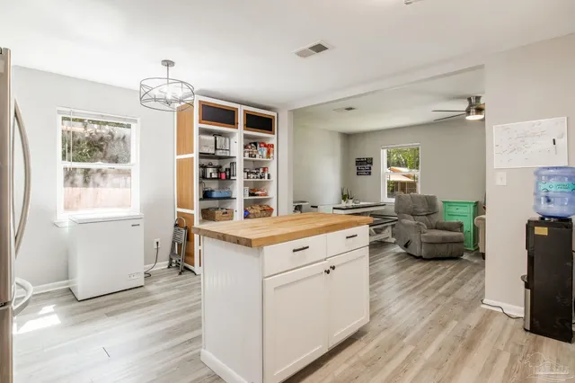 a kitchen that has a lot of cabinets in it and wooden floors