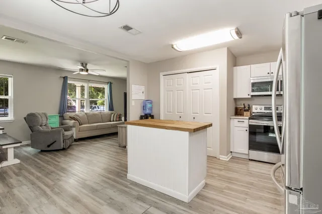 a kitchen with stainless steel appliances a stove a sink dishwasher a refrigerator white cabinets and wooden floor