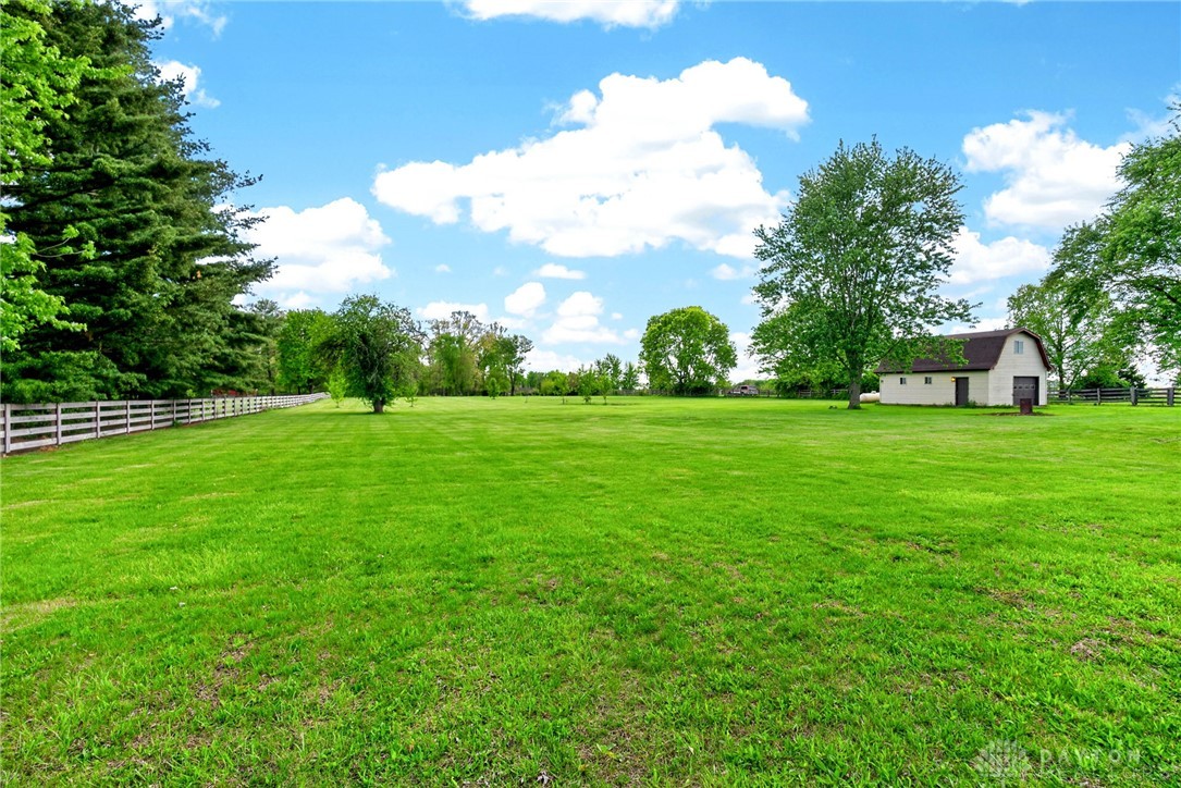 1005 Free Road New Carlisle, OH 45344 - Photo 35 of 43 Expansive green acreage with a charming outbuilding under a vibrant blue sky.