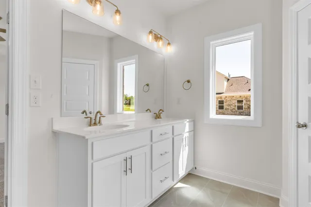 a spacious bathroom with a double vanity sink a mirror and next to a window
