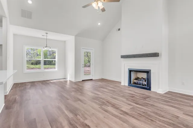 a view of an empty room with wooden floor fireplace and a window