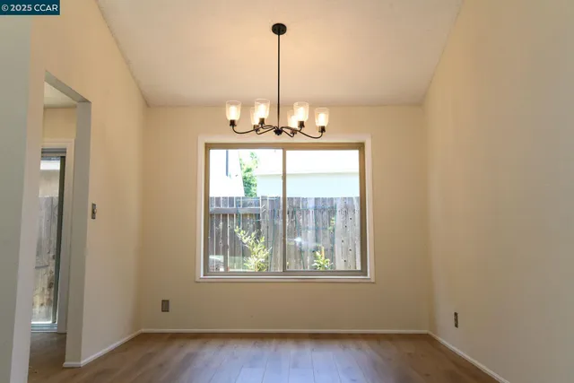 a view of a room with wooden floor chandelier and windows