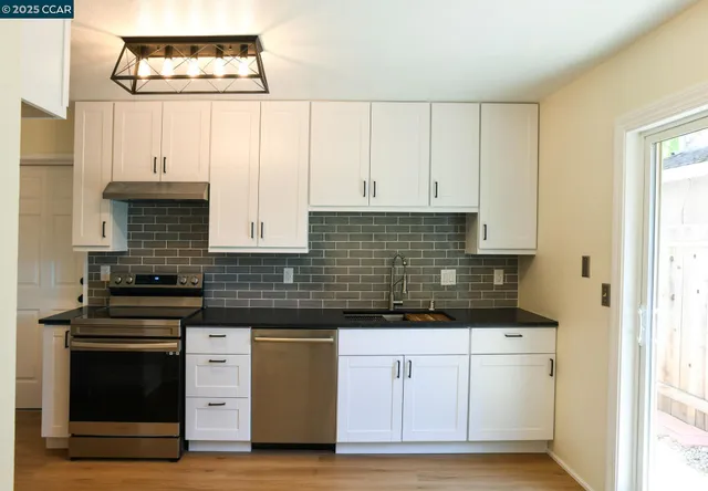 a kitchen with granite countertop white cabinets and stainless steel appliances
