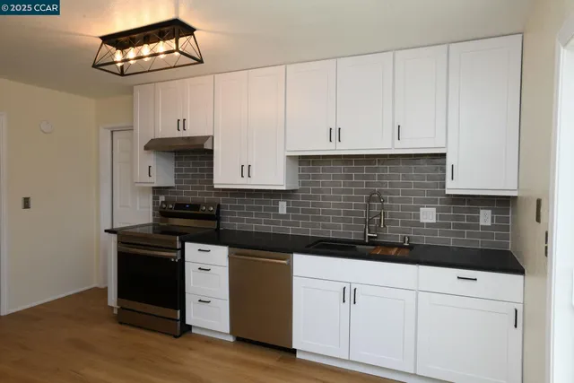 a kitchen with stainless steel appliances a stove a sink and white cabinets