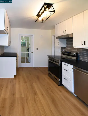 a kitchen with stainless steel appliances a stove a sink and white cabinets