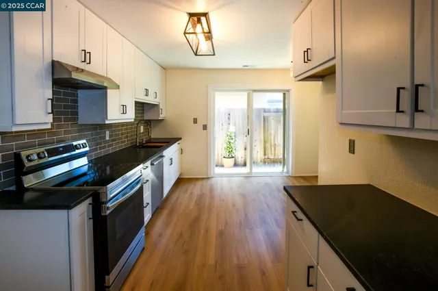 a kitchen with stainless steel appliances granite countertop a stove a sink and a refrigerator