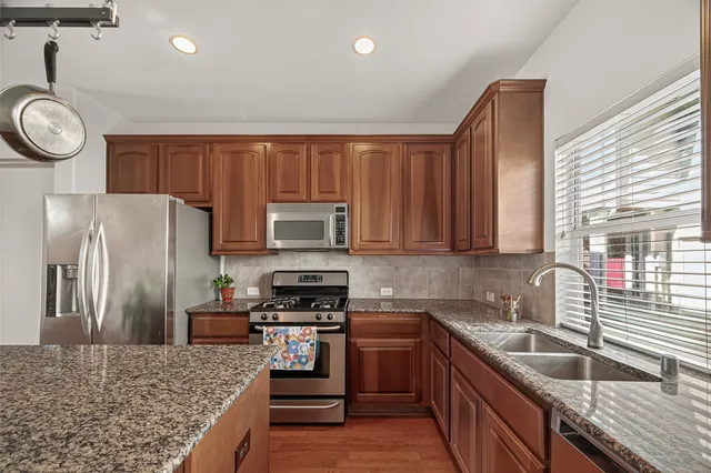 a kitchen with granite countertop a sink a stove top oven a refrigerator and cabinets