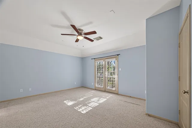 an empty room with windows and ceiling fan