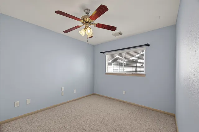 an empty room with a window and ceiling fan