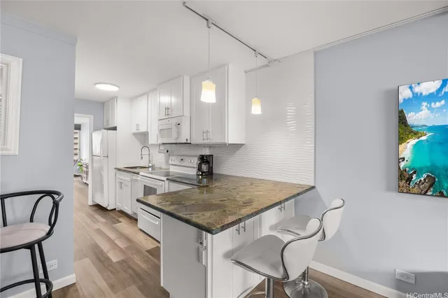 a kitchen with stainless steel appliances granite countertop a table chairs in it and wooden floors