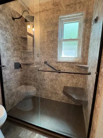a bathroom with a granite countertop sink a toilet and shower
