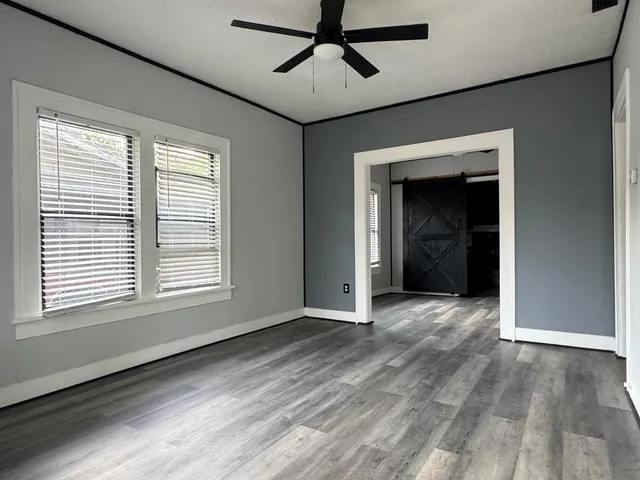 a view of an empty room with a window and wooden floor