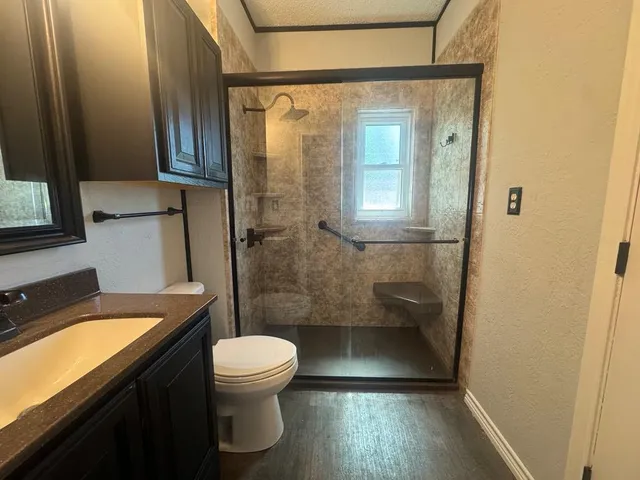 a bathroom with a granite countertop toilet a sink and a shower
