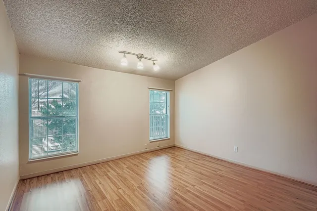 an empty room with wooden floor cabinet and windows